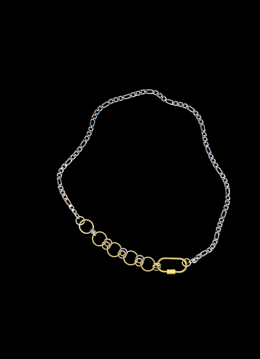 Stainless steel chain necklace with a gold carabiner clasp and chainmail detail on a black background