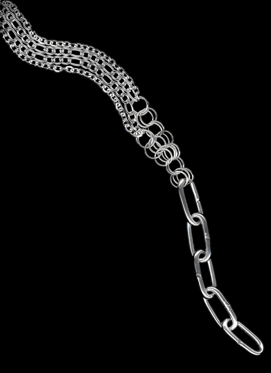 A silver Figaro chain lariat necklace with a diamond-cut chain pendant and chainmail detail, displayed against a black background.