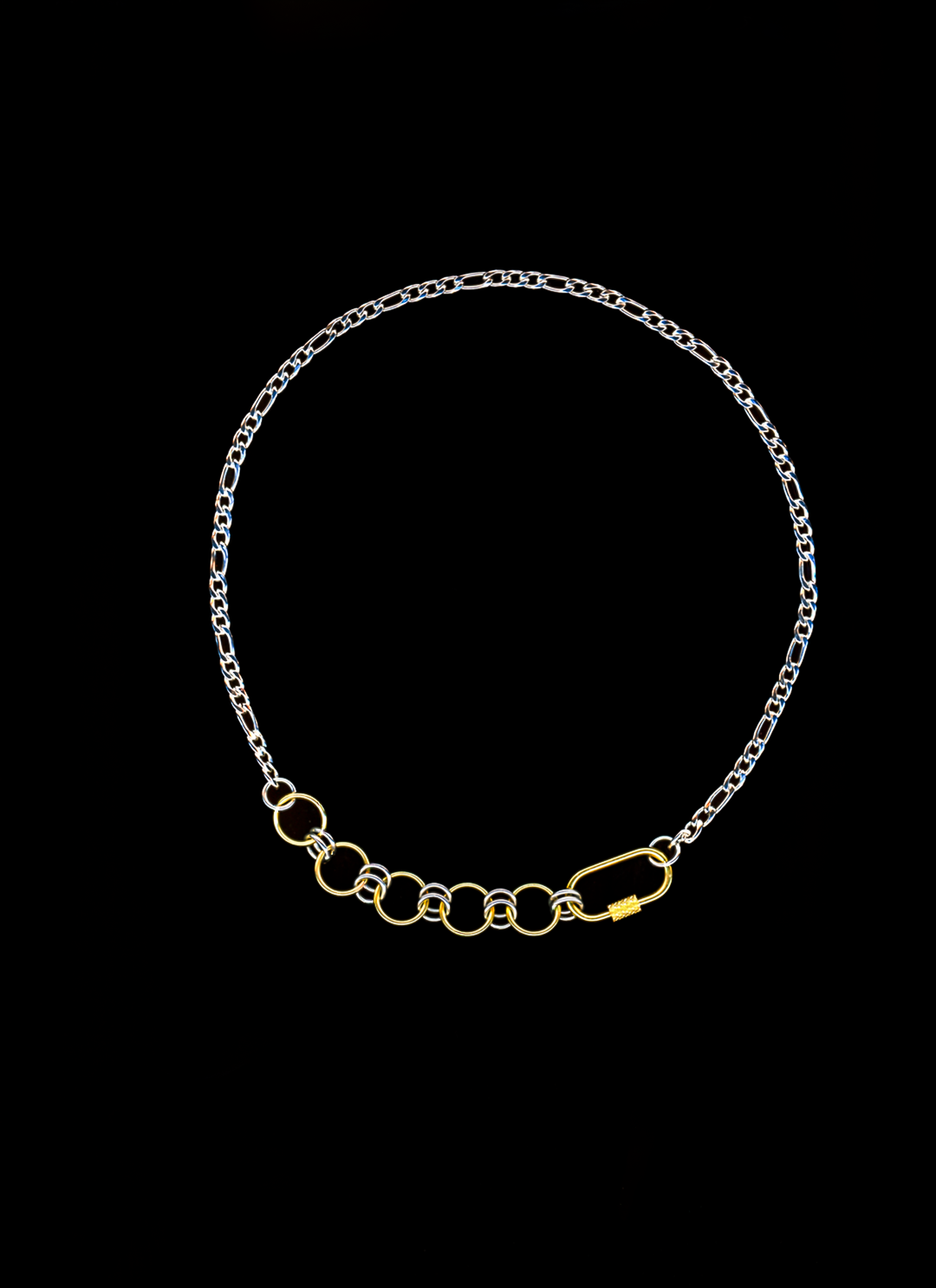 Mixed metal chain necklace with gold carabiner closure and chainmail detail on a black background