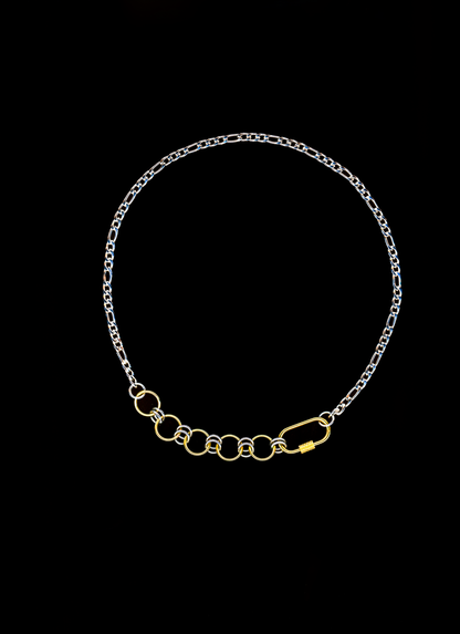 Mixed metal chain necklace with gold carabiner closure and chainmail detail on a black background