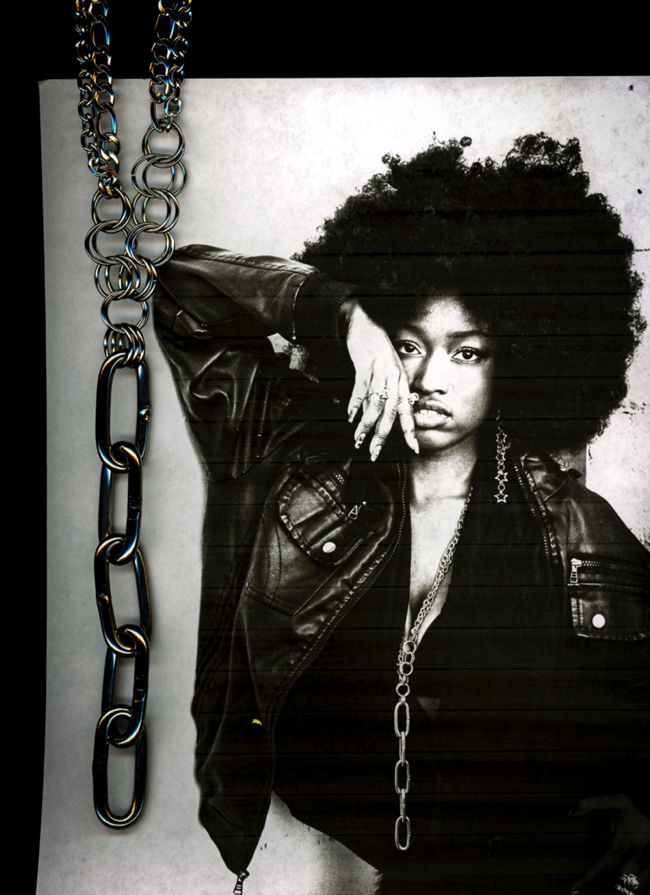 black and white photocopy scan edit of person with large afro and chain necklace against a plain background with the same chain overlayed in the scan.