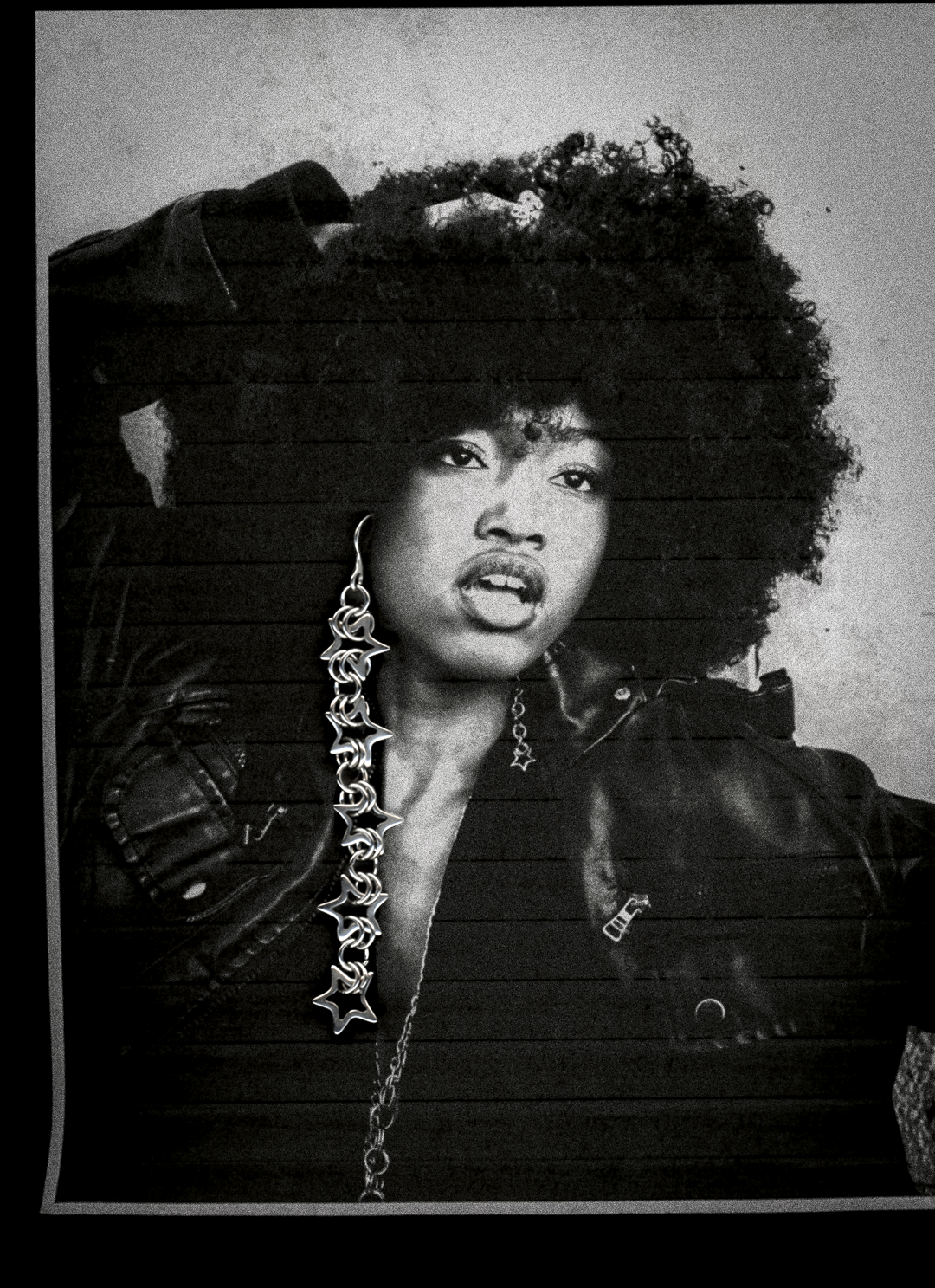 Person wearing a leather outfit with a detailed chain necklace and chainmail star earrings against a textured background