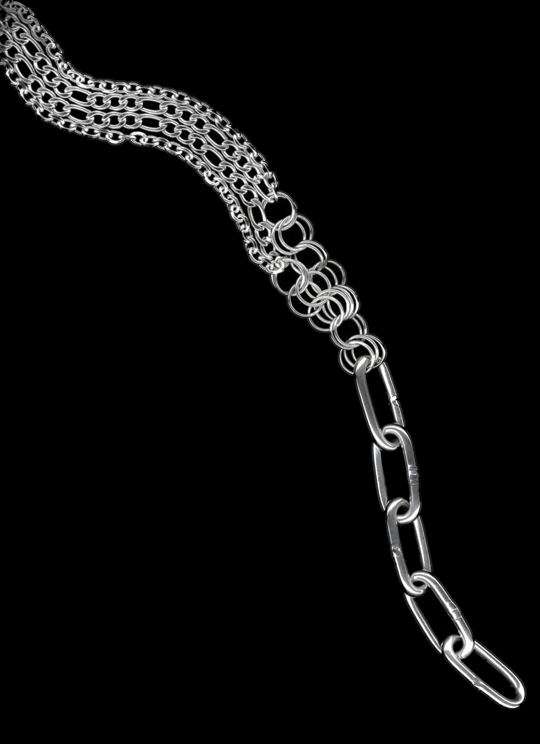 A silver Figaro chain lariat necklace with a diamond-cut chain pendant and chainmail detail, displayed against a black background.