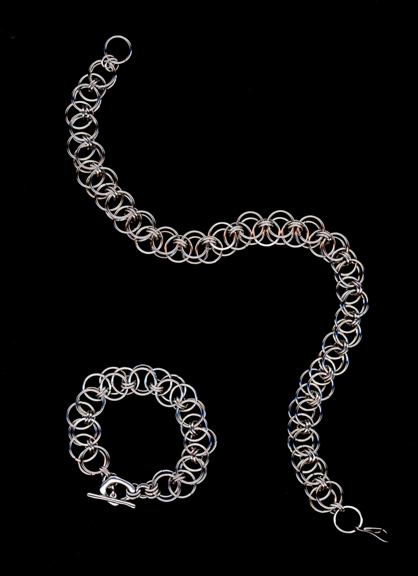 Silver chainmail necklace and bracelet on a black background