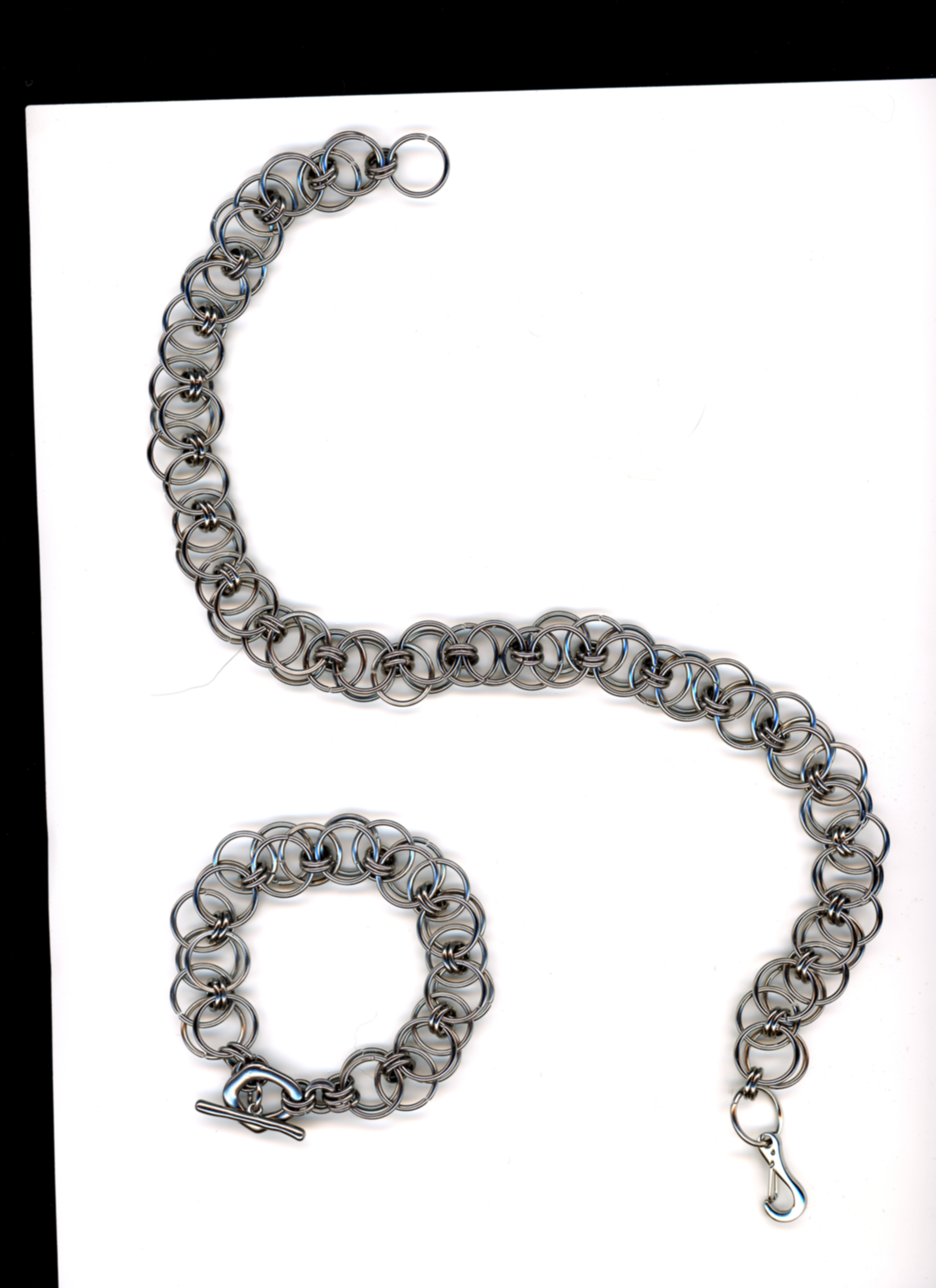 Silver chainmail necklace and bracelet set on a white background