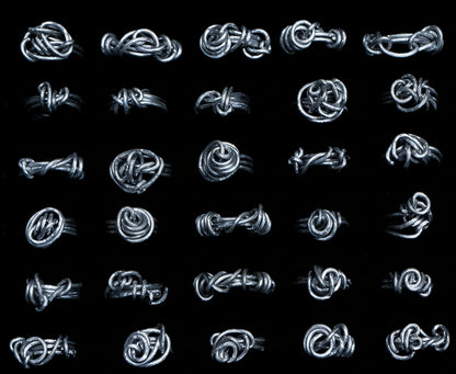 A collection of various continuous thread rings made from metal, displayed against a black background.