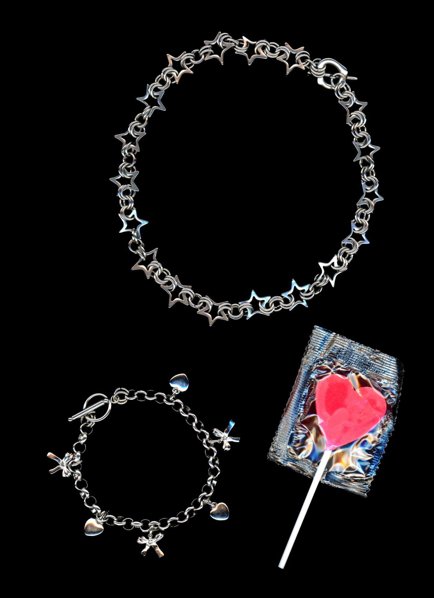 Chainmail star necklace and charm bracelet with 3-d bow and heart charms on a black background with a bright pink heart shaped lollypop