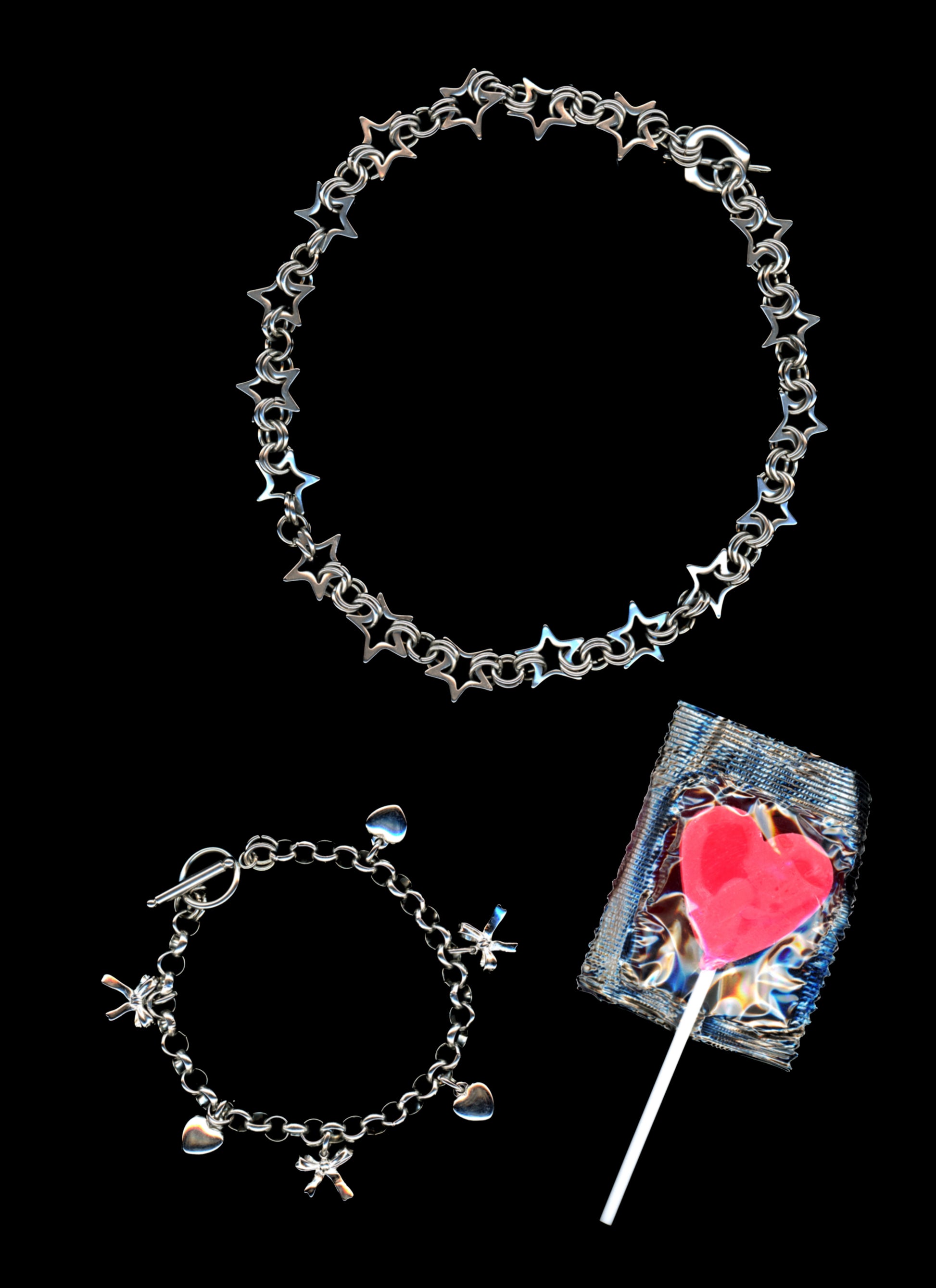 Chainmail star necklace and charm bracelet with 3-d bow and heart charms on a black background with a bright pink heart shaped lollypop