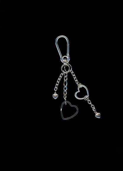 A silver stainless steel heart-shaped carabiner keychain with additional heart charms and Figaro chains on a dark background.