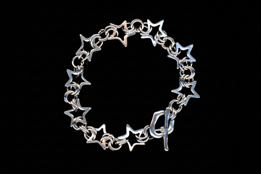 A silver-colored chainmail bracelet with a star pattern and a toggle closure.