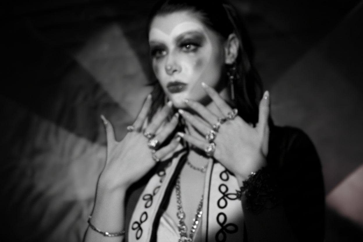 Person with heart clown makeup and jewelry in a stylized setting