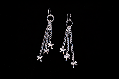 A pair of stainless steel chain-drop bow earrings with multiple small bows attached to figaro chains, displayed against a black background.