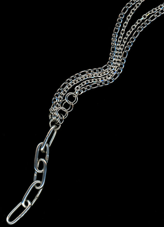 A silver Figaro chain lariat necklace with a diamond-cut chain pendant and chainmail detail, displayed against a black background.