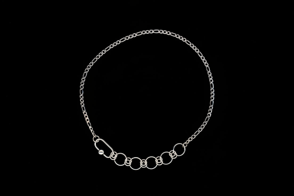 Silver chain necklace with chainmail detail on a black background