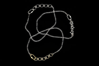 Silver chain necklaces, one with with star-shaped chainmail detail on a black background