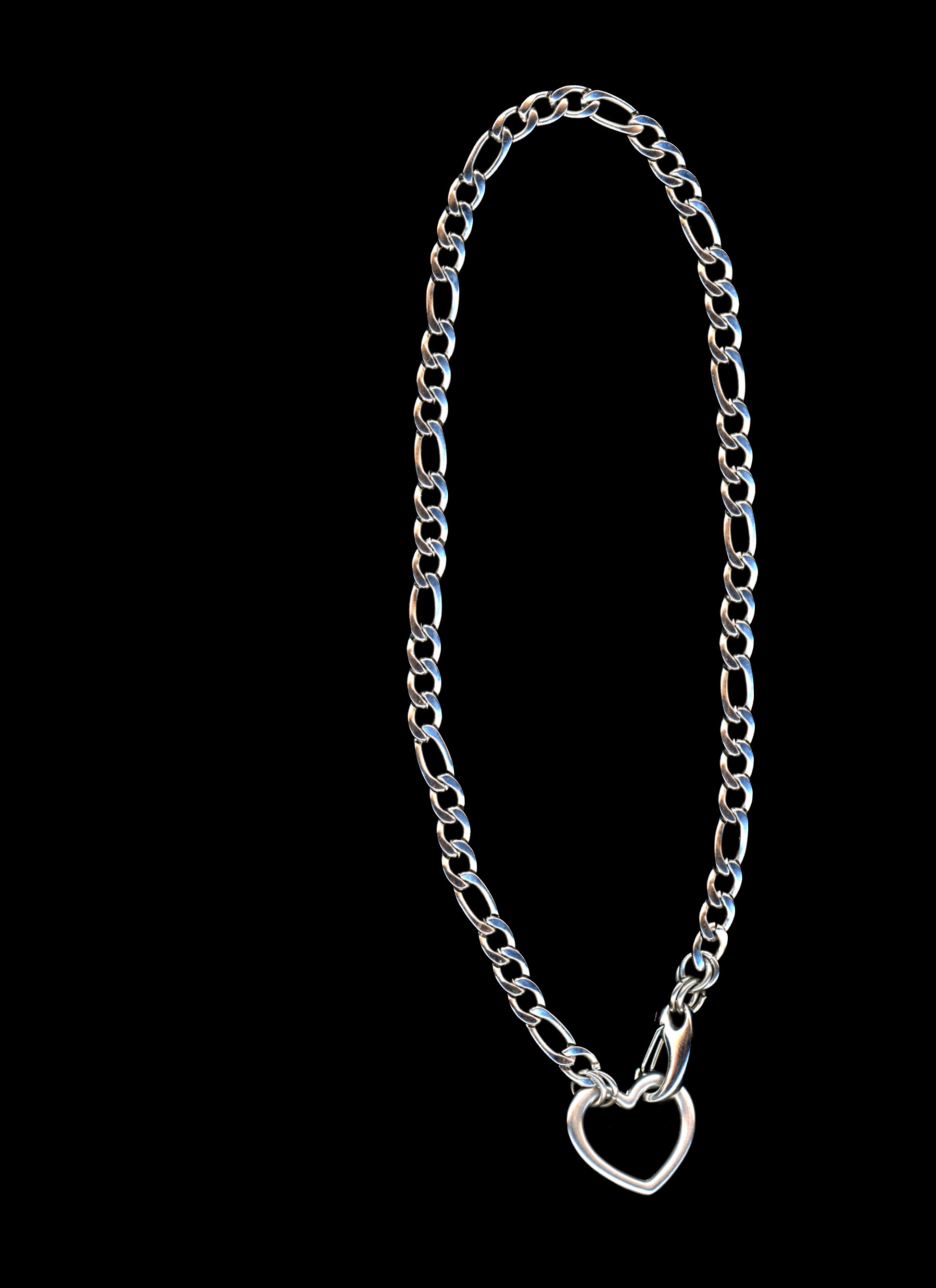 Silver chain necklace with a heart-shaped closure on a black background