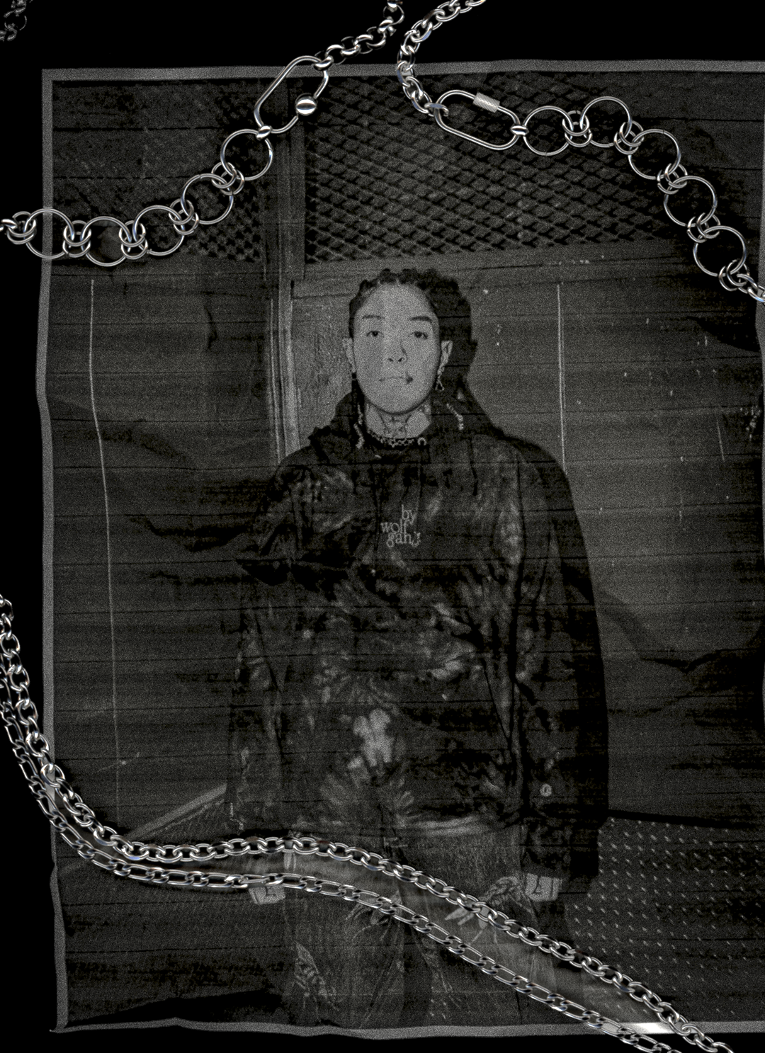 Scanned photo of person wearing a dark jacket with chains in front of a textured wall with bywolfgang chains overlayed on scanner.