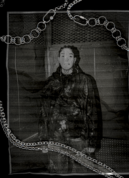 Scanned photo of person wearing a dark jacket with chains in front of a textured wall with bywolfgang chains overlayed on scanner.
