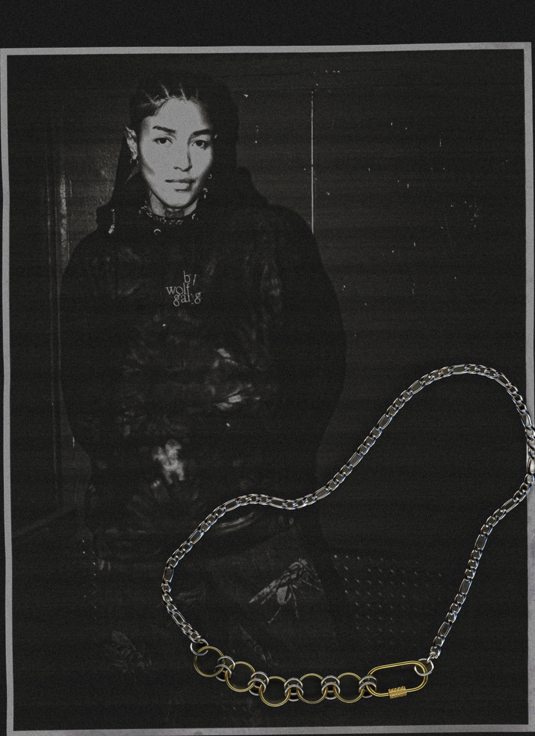 Person wearing an embroidered bywolfgang stonewash hoodie in a freight elevator in a crumpled photocopy scan edit with the sutton mixed-metal carabiner necklace overlayed. 